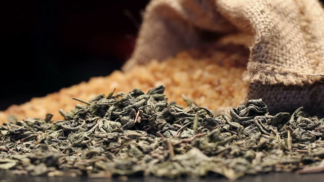 Brown sugar in gunny sack and a pile of dried green tea leaves, rotating