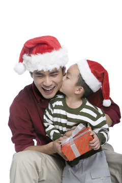 Father and son with Santa hats holding gift box
