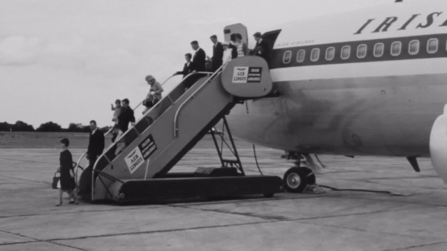Wide shot of passengers disembarking airplane
