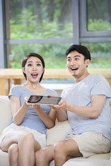 Young couple cheering with digital tablet