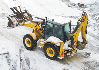 Tractor shoveling snow on the street.