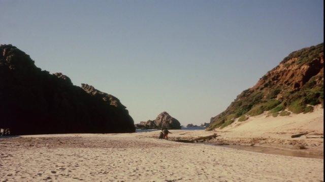 Rear view of man chasing woman on the beach, 1960s
