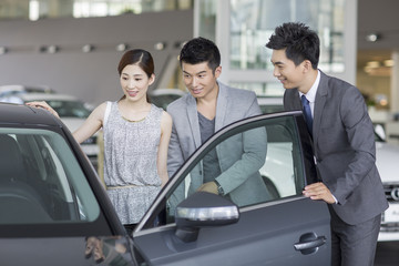 Young couple choosing car in showroom