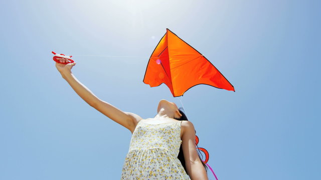 Smiling Asian Chinese girl playing with red kite on beach 