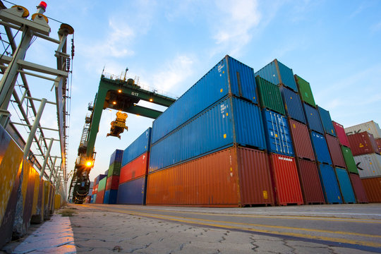 Cranes and multi-colored stack of cargo containers at dusk