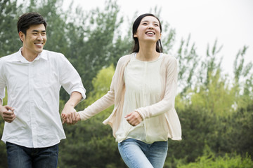 Happy young couple holding hands running