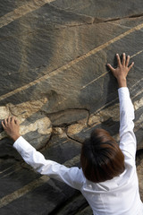 A businesswoman climbing a rock face
