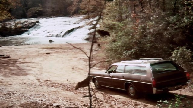 Station wagon driving on dirt road towards river