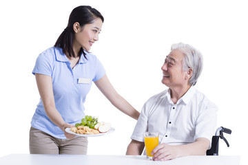 Obraz na płótnie Canvas Nursing assistant serving food for disabled senior man