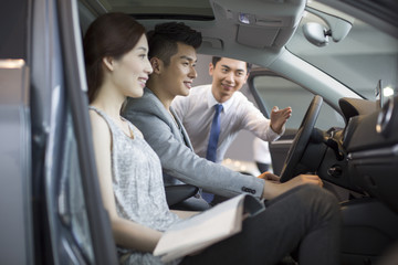 Young couple choosing car in showroom