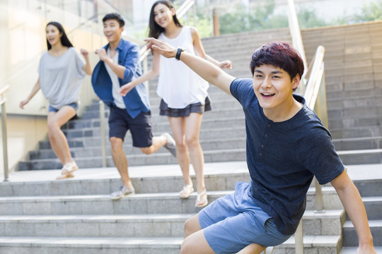 Young Man Sliding Down Banister On Steps