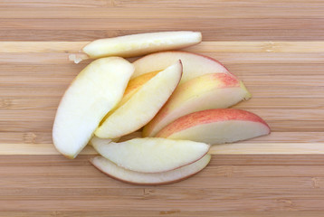 Red apple slices on a wood cutting board