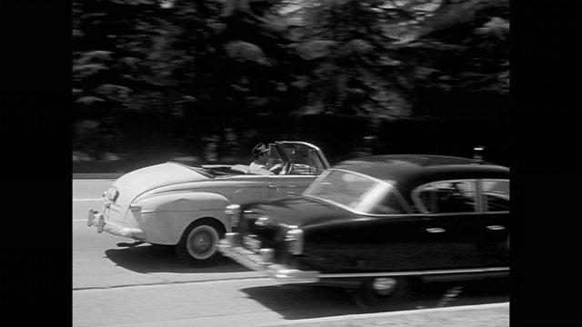Car stopping by broken down police car on road, 1950s