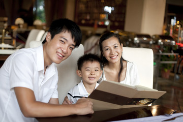 Portrait of a happy family looking through a menu