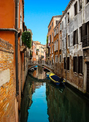 Fototapeta na wymiar Beautiful view of the bridge over narrow venetian сanal with boats and colorful facades of old medieval houses. Venice, Italy 