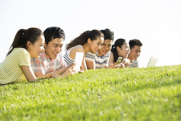 Cheerful young adults lying down on grass playing together
