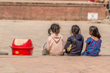 3 Mädchen sitzen neben Mülleimer
