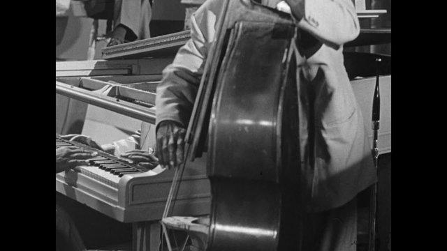 Medium shot of  musicians playing double bass and piano in band, 1950s