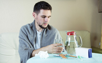 Portrait Of Young man On Sofa With Medicine And Glass Of Water.