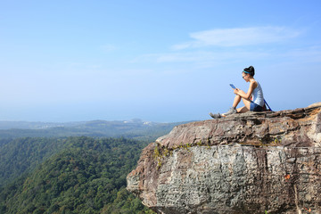 woman hiker use digital tablet at mountain peak