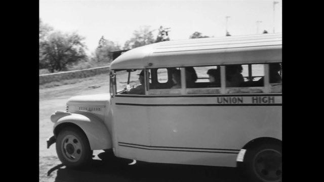 School bus departing from high school, 1940s