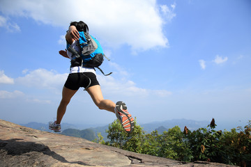 young asian woman hiker running on mountain peak cliff