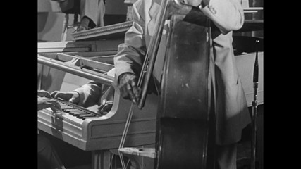 Medium shot of pianist accompanying bass player in band, 1950s