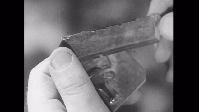 Closeup of man rotating broken harmonica part, 1930s