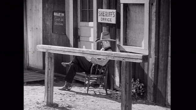Cowboy reading newspaper outside sheriff's office, 1930s