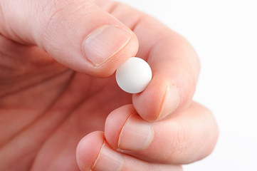 macro of white pill in hand