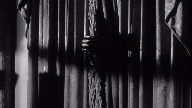 Mysterious man with claw hands peeks through curtains