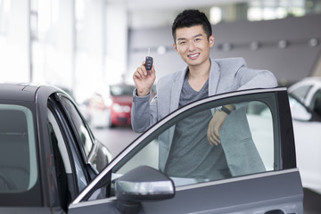 Fototapeta na wymiar Young man buying car in showroom
