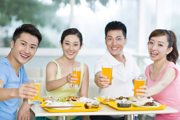 Young adults celebrating with orange juice
