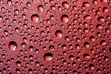 Red water drops on glass surface texture.