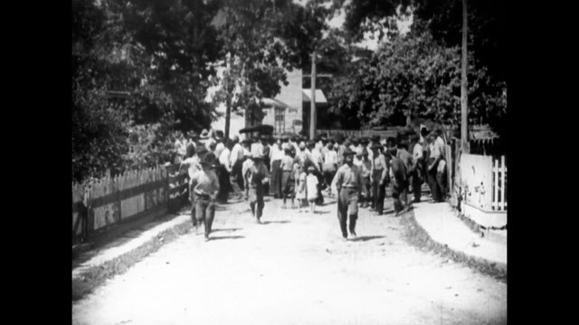 Wide shot of crowd in street dispersing, 1920s