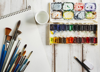 Naklejka premium Used water-color paint-box, watercolor paper and paint brush.