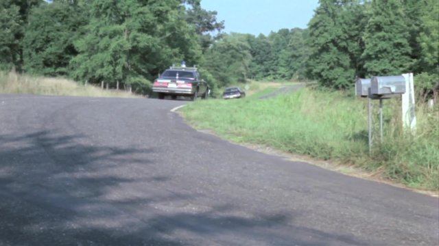 Police car chasing man in station wagon on country road
