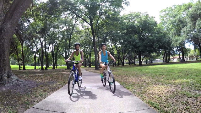 Young slim multi ethnic girls riding bicycles in park