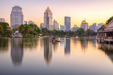 Business district cityscape from a park with Twilight Time from Lumpini Park, Bangkok, Thailand