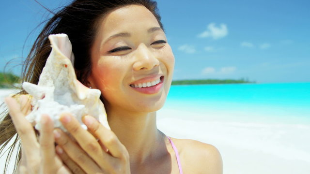 Asian Chinese girl holding conch shell at leisure resort