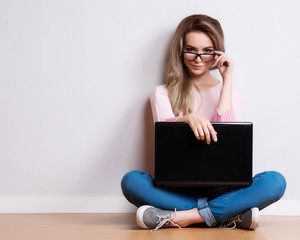 Young creative woman sitting in the floor with laptop./ Casual blogger woman