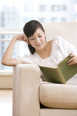 Asian woman reading on a sofa