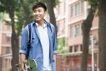Male college student with skateboard on campus © Blue Jean Images