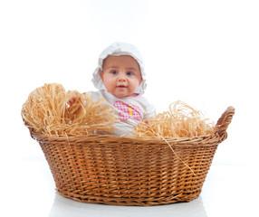 Cute female toddler in a straw basket