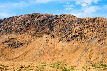 Fototapeta na wymiar Rocky dry yellow cliff ridge with eroded channels