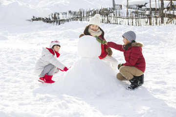 Happy children making snowman together