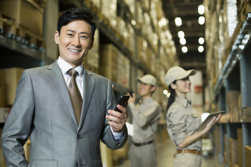 Businessman with mobile phone in warehouse