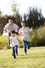 Fototapeta premium Young Chinese family running in a field
