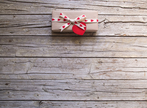 valentine gift box and red heart shape tag on wooden board