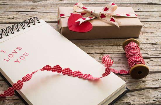 gift, ribbon and notebook with I love you